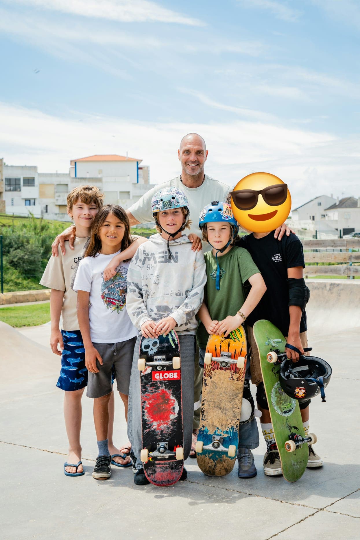 A coach standing with five boys holding their skateboards at the skatepark